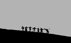 silhouettes of people holding hands on top of a hill with the sky in the background