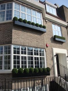 a brick building with many windows and plants on the balconies