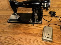 an old sewing machine sitting on top of a wooden table next to a cell phone