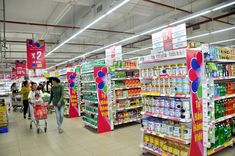 people shopping in a grocery store filled with drinks