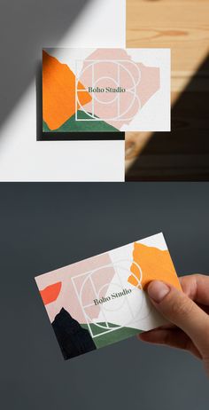 two business cards in different colors and shapes, one being held up by a person's hand