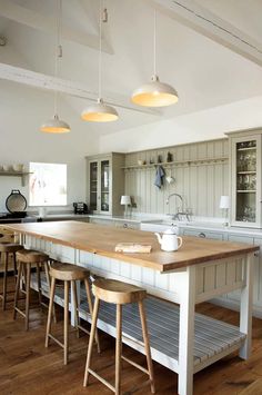 a kitchen island with stools in front of it and lights hanging from the ceiling