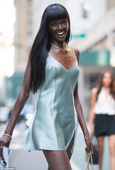 a woman walking down the street with a handbag in her other hand and smiling