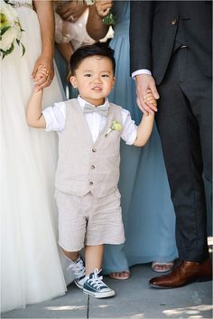 a little boy is holding the hand of his father