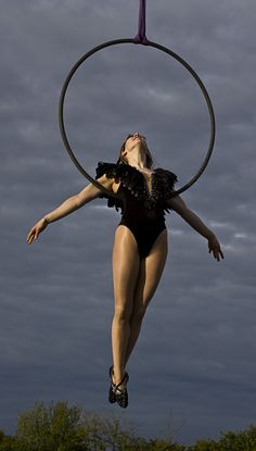 a woman in a black leotard with a hoop around her neck and legs