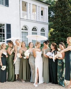 a group of women standing next to each other in front of a building holding umbrellas