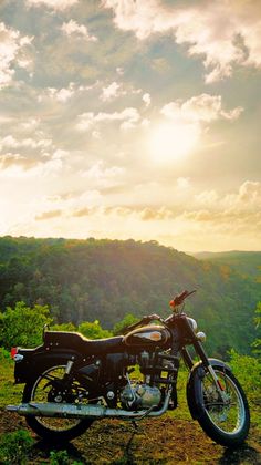 a motorcycle parked on top of a lush green hillside