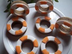 four orange and white donuts on a plate with some spools in the middle