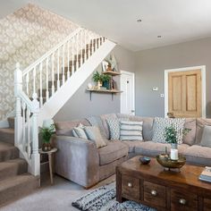 a living room filled with furniture and a stair case next to a wooden coffee table