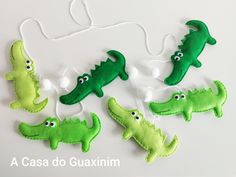 four felt alligators with eyes and tails are hanging from a string on a white surface