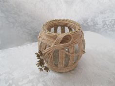 a small basket with twine and pine cones tied to it on a white surface