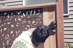 a man is working on an outdoor screen in front of a house with wood siding