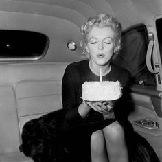 a black and white photo of a woman blowing out a candle on her birthday cake