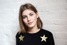 a young woman with blonde hair wearing a black shirt and gold stars on her sleeves