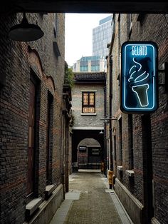 an alley way with brick buildings and a neon sign