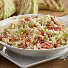 a white bowl filled with coleslaw on top of a wooden table