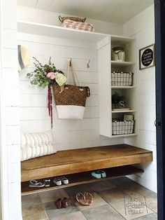 a wooden bench sitting in the middle of a room next to a shelf filled with shoes