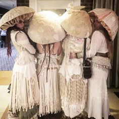 three women in white dresses and hats standing next to each other with umbrellas on their heads