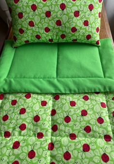 a green bed with red ladybugs on it and matching pillow cases in the same color