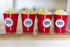 three red cups filled with popcorn sitting on top of a wooden table