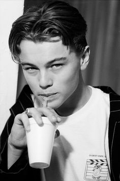 black and white photograph of a young man drinking from a cup