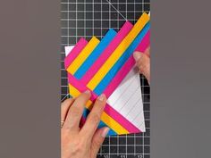 someone is cutting out colored papers on a piece of paper that has been cut into squares