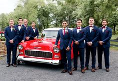 a group of men standing next to each other in front of a red car