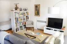 a living room filled with furniture and a flat screen tv sitting on top of a book shelf