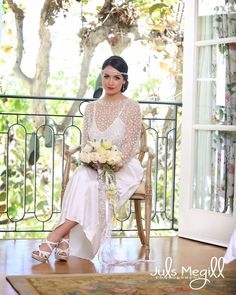 a woman is sitting on a chair with flowers in her hand and holding a bouquet