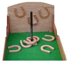 a wooden toy set with horseshoes and numbers in it on a green mat area