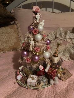 a small christmas tree sitting on top of a bed next to a teddy bear and other decorations