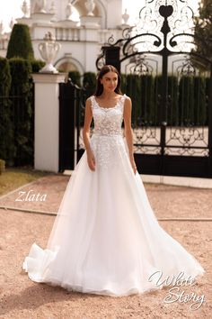 a woman standing in front of a gate wearing a wedding dress