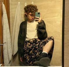 a man taking a selfie in front of a bathroom mirror with his feet up