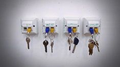 four keys are hanging on the wall in front of three electrical outlets with key chains attached to them