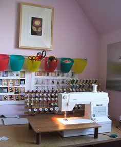 a sewing machine sitting on top of a wooden table next to a shelf filled with cups