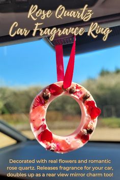 a pink ring hanging from the dashboard of a car with red ribbon around it's edge