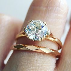 a close up of a person's hand holding a ring with a diamond in it