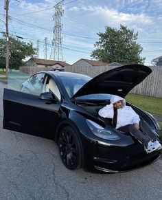 a man sitting on the hood of a black car