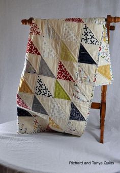 a quilt on a wooden chair with white background and text overlay that says,'this is an image of a multicolored patchwork quilt hanging from a clothes rack