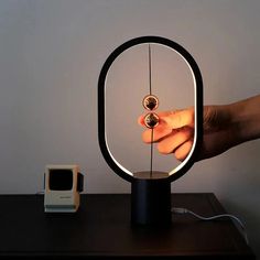 a person is holding an object in front of a lamp that looks like a ring