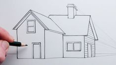 a person drawing a house with a pencil