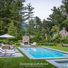 a pool surrounded by lush green trees and lawn furniture with an outdoor fireplace in the background