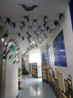 a hallway decorated with paper bats and hanging from the ceiling in an office building or school