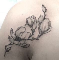 the back of a woman's shoulder with flowers tattooed on her left side breast