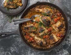 two pans filled with food on top of a gray counter next to silverware