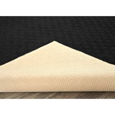 a black and white rug with a triangle on the bottom, in front of a wooden floor