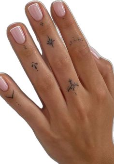 a woman's hand with two small tattoos on her left thumb and one finger