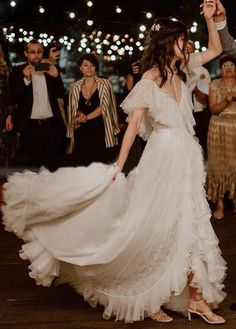 a woman in a white dress is dancing with other people and lights on the background