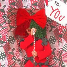 a doll is dressed in red and black with a christmas tree on her head, holding a candy cane