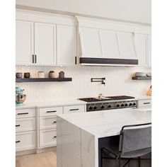 a kitchen with white cabinets and marble counter tops